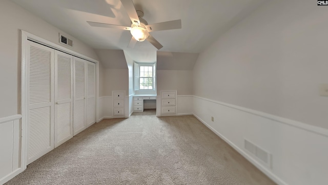 unfurnished bedroom featuring ceiling fan, light colored carpet, a closet, and vaulted ceiling