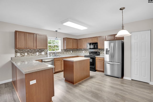 kitchen featuring black appliances, a center island, kitchen peninsula, light hardwood / wood-style flooring, and decorative light fixtures