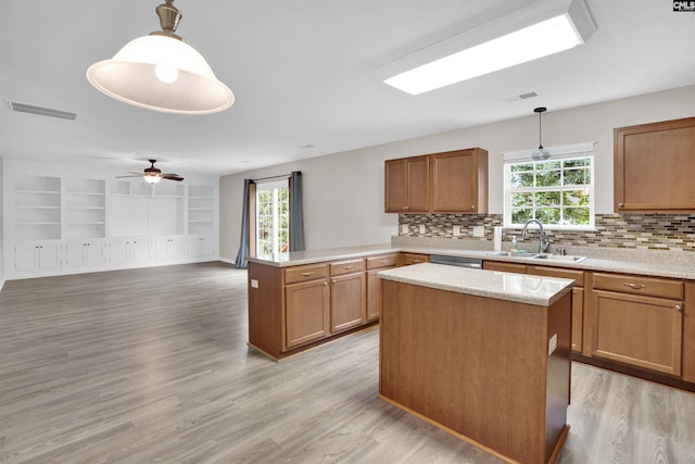 kitchen with decorative light fixtures, a center island, ceiling fan, and sink