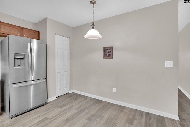 kitchen featuring stainless steel fridge, light hardwood / wood-style flooring, and pendant lighting