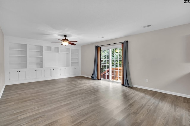 empty room featuring ceiling fan, built in features, and light hardwood / wood-style flooring