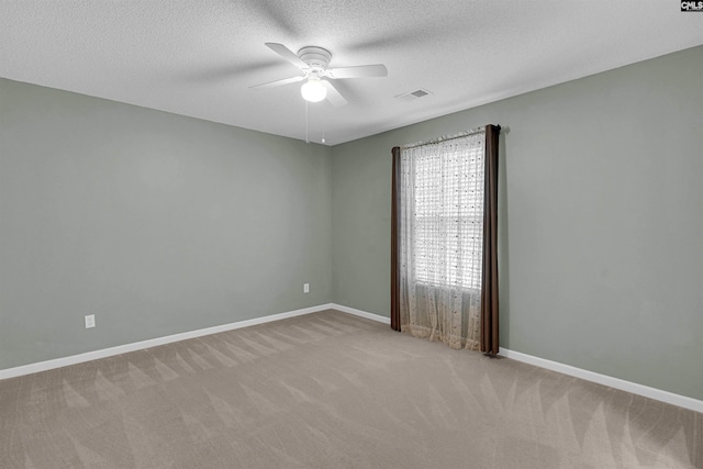 carpeted spare room featuring a textured ceiling and ceiling fan