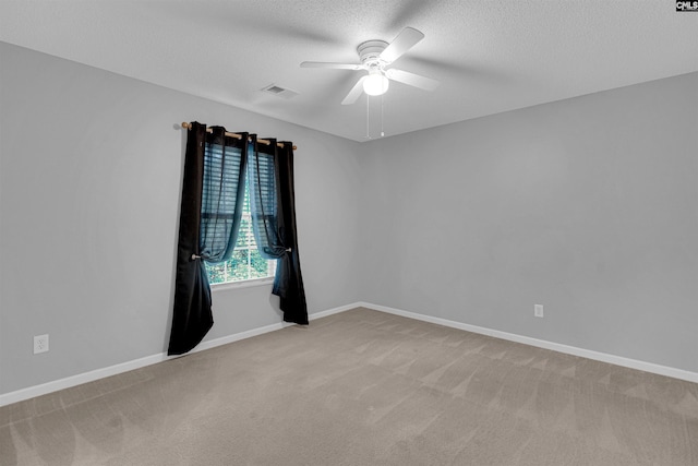 empty room featuring ceiling fan, light carpet, and a textured ceiling