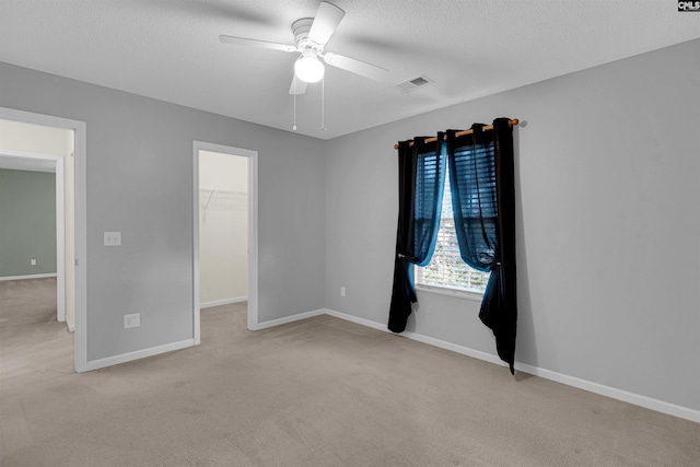 carpeted spare room featuring ceiling fan and a textured ceiling