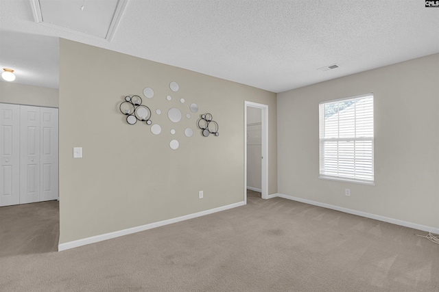 spare room with a textured ceiling and light carpet