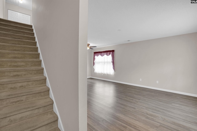 staircase with ceiling fan and hardwood / wood-style floors