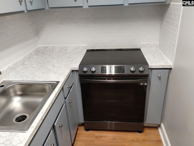 kitchen with tasteful backsplash, gray cabinets, electric stove, and light hardwood / wood-style floors