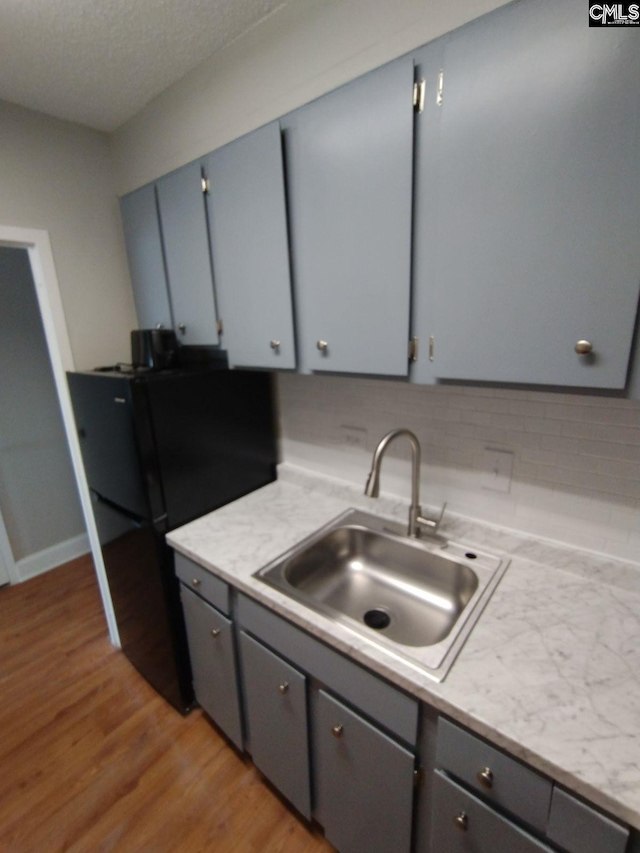 kitchen with sink, black fridge, light hardwood / wood-style floors, and gray cabinets