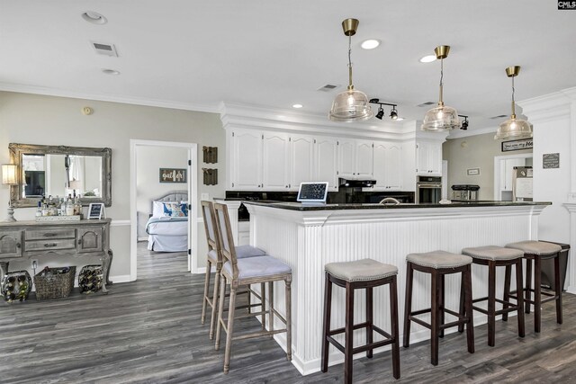 kitchen with stainless steel oven, a breakfast bar area, hanging light fixtures, and white cabinetry