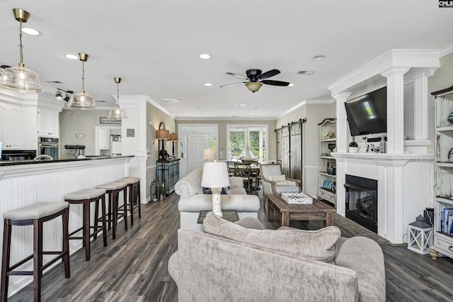 living room featuring ornamental molding, dark hardwood / wood-style flooring, ceiling fan, and a barn door