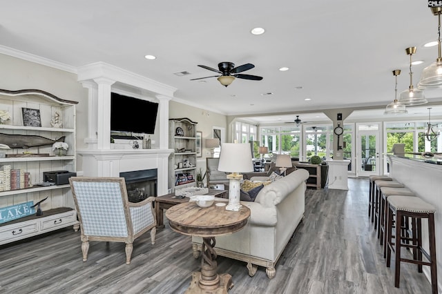 living room featuring dark wood-type flooring, ceiling fan, and ornamental molding