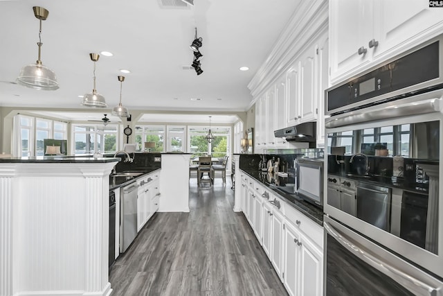 kitchen featuring appliances with stainless steel finishes, hanging light fixtures, ornamental molding, white cabinets, and sink