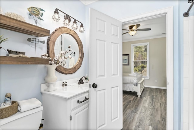 bathroom with toilet, wood-type flooring, vanity, ornamental molding, and ceiling fan