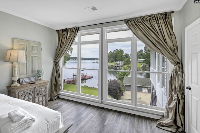 bedroom with hardwood / wood-style floors, ornamental molding, and a water view