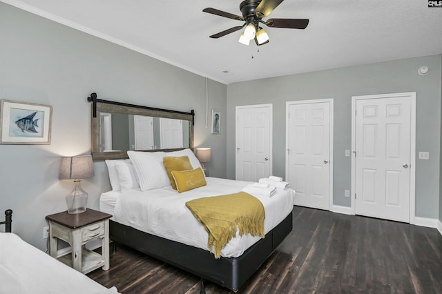 bedroom with dark hardwood / wood-style flooring, two closets, and ceiling fan