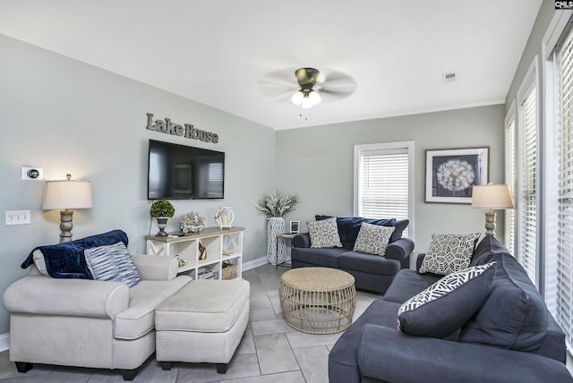 living room with ceiling fan, a wealth of natural light, and light tile patterned floors