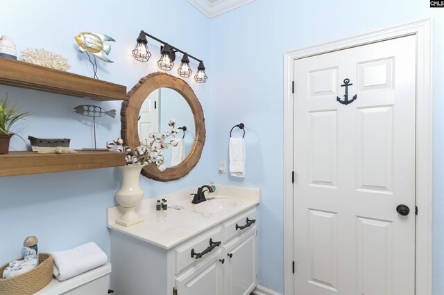 bathroom with toilet, vanity, and crown molding