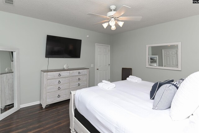 bedroom with ceiling fan, a textured ceiling, and dark hardwood / wood-style floors