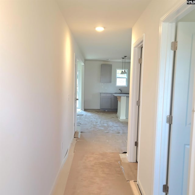 corridor with baseboards and a sink