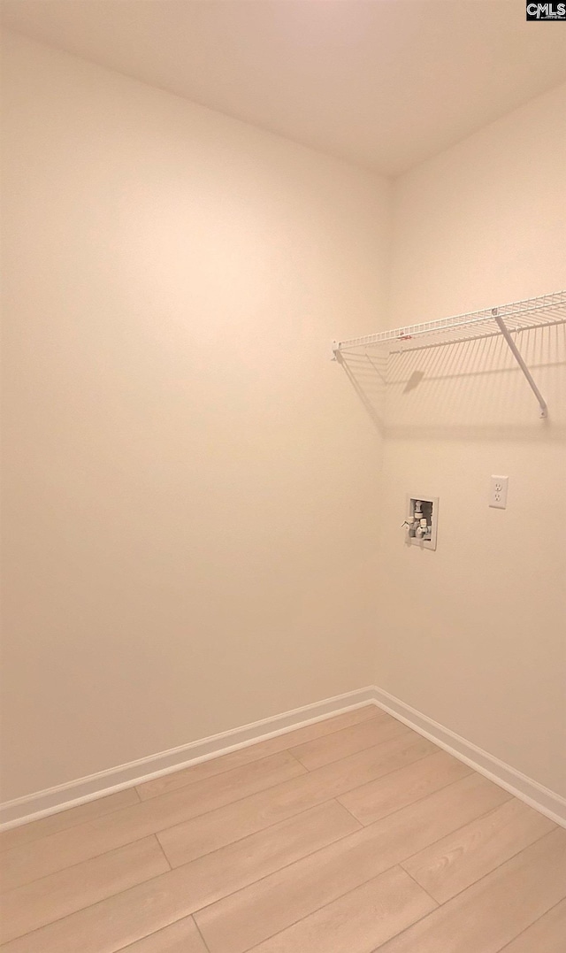 clothes washing area with baseboards, light wood-style floors, hookup for a washing machine, and laundry area