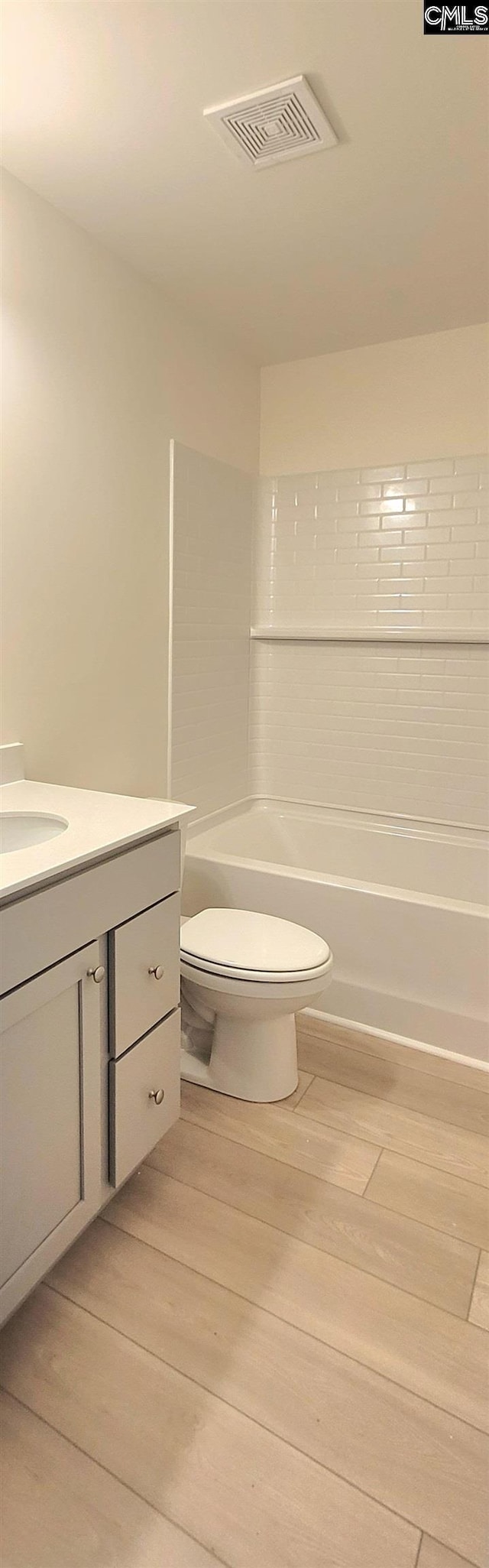 full bathroom featuring visible vents, toilet, vanity, and wood finished floors