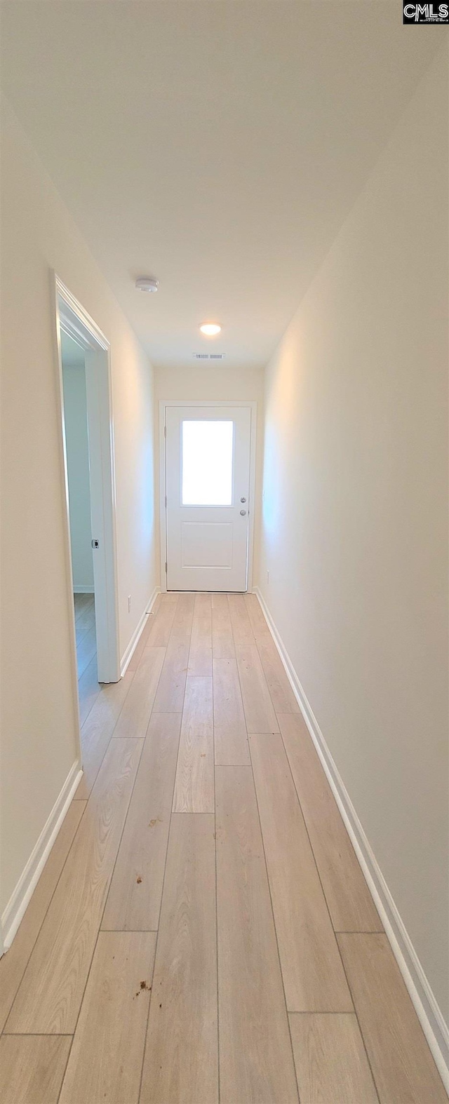hallway with light wood-type flooring, baseboards, and visible vents