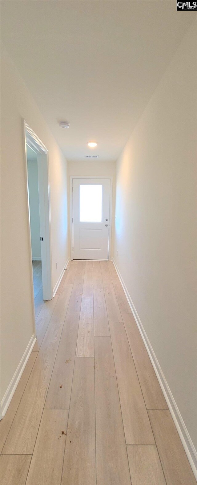 corridor featuring light wood-type flooring, baseboards, and visible vents