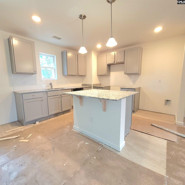 kitchen with a kitchen island, sink, gray cabinets, and hanging light fixtures