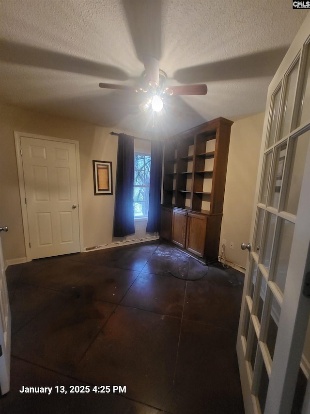 unfurnished room with ceiling fan and a textured ceiling