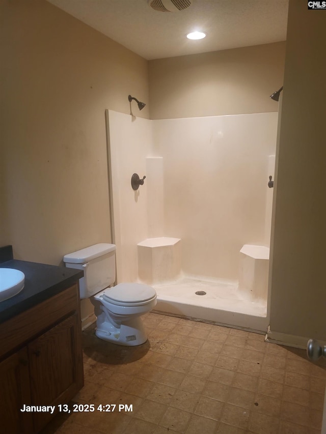 bathroom featuring vanity, toilet, and walk in shower