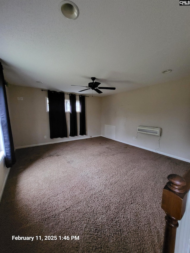 empty room featuring ceiling fan, a wall mounted AC, carpet floors, and a textured ceiling