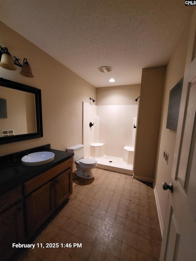 bathroom with vanity, a textured ceiling, toilet, and walk in shower