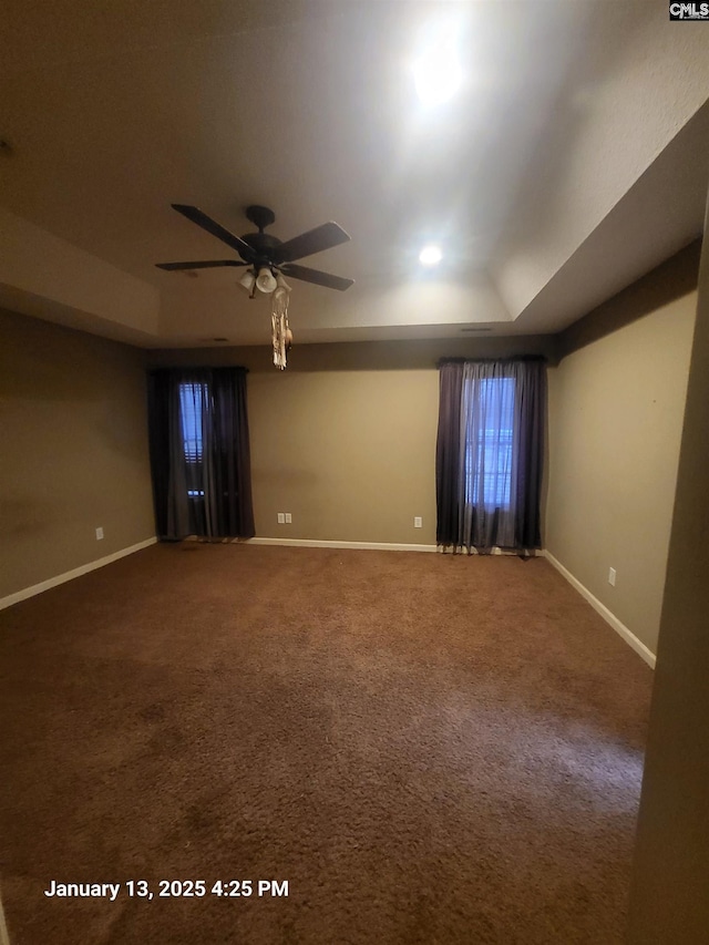 carpeted spare room featuring a tray ceiling and ceiling fan