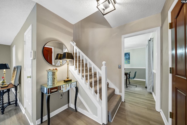 stairs with a textured ceiling and hardwood / wood-style floors