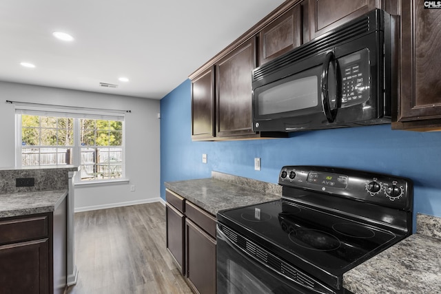 kitchen with light stone countertops, light wood-type flooring, black appliances, and dark brown cabinetry