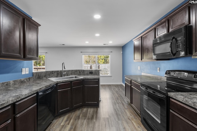 kitchen featuring wood-type flooring, black appliances, plenty of natural light, dark brown cabinetry, and sink