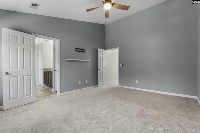 unfurnished bedroom with ceiling fan, light colored carpet, and connected bathroom