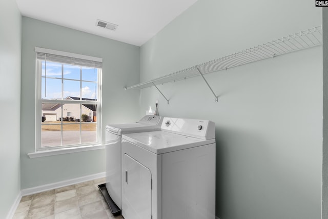 clothes washing area with washing machine and dryer and a healthy amount of sunlight