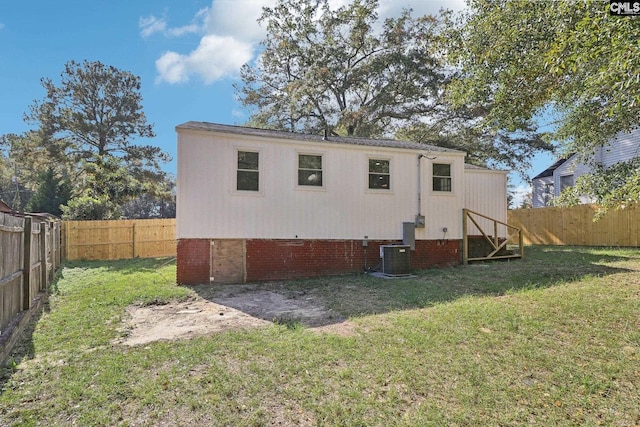 back of house with central AC unit and a lawn