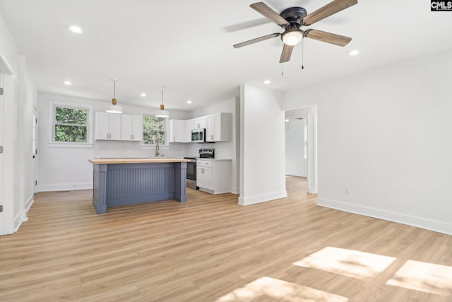 kitchen featuring stainless steel appliances, white cabinets, decorative light fixtures, tasteful backsplash, and a kitchen island