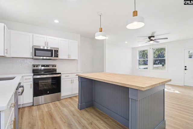 kitchen with pendant lighting, a center island, white cabinetry, appliances with stainless steel finishes, and ceiling fan