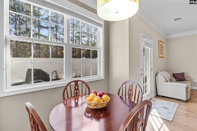 dining room with light wood-type flooring and ornamental molding