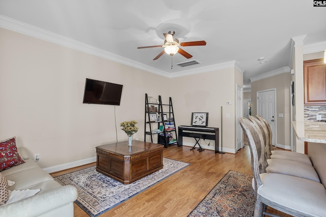 living room with light hardwood / wood-style floors, ceiling fan, and ornamental molding