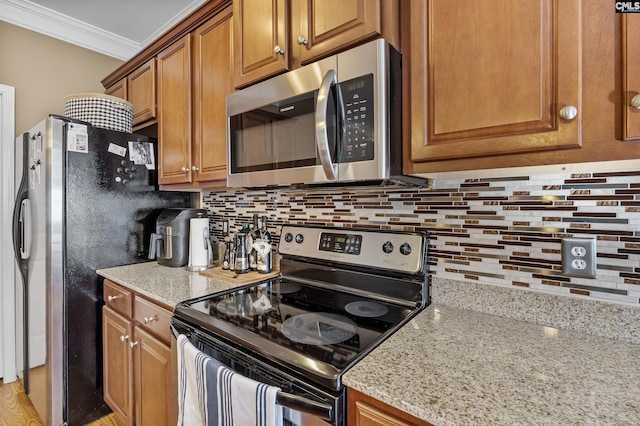 kitchen with light stone countertops, ornamental molding, tasteful backsplash, and appliances with stainless steel finishes