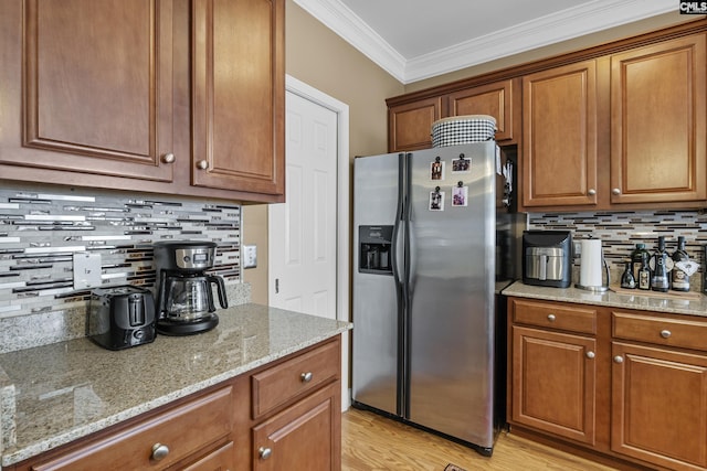 kitchen with decorative backsplash, light stone counters, crown molding, and stainless steel fridge with ice dispenser