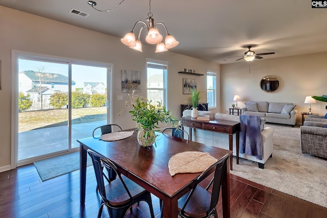 dining room with ceiling fan with notable chandelier and wood-type flooring