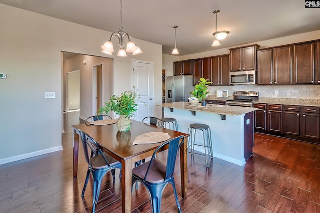 kitchen with stainless steel appliances, an inviting chandelier, a kitchen bar, a kitchen island, and pendant lighting