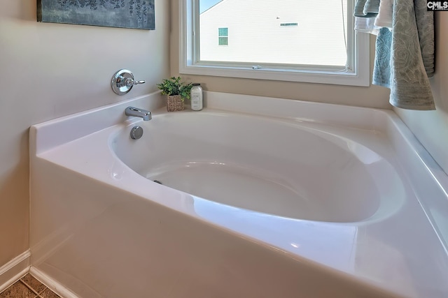 bathroom featuring a healthy amount of sunlight, a bathtub, and tile patterned flooring