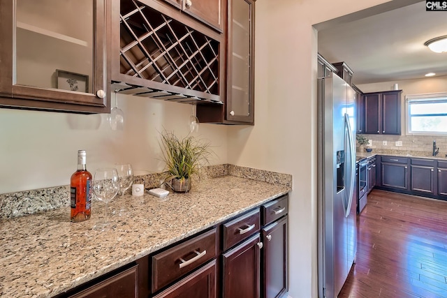 kitchen featuring dark hardwood / wood-style flooring, light stone counters, dark brown cabinets, and stainless steel fridge with ice dispenser