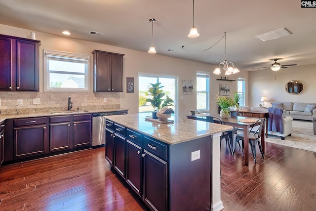 kitchen featuring stainless steel dishwasher, decorative light fixtures, tasteful backsplash, a kitchen island, and sink